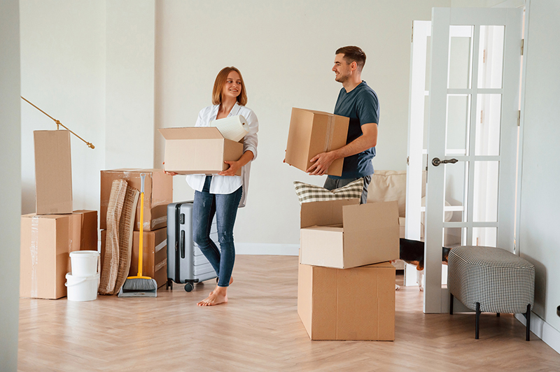 Holding boxes. Young couple moving to new home.