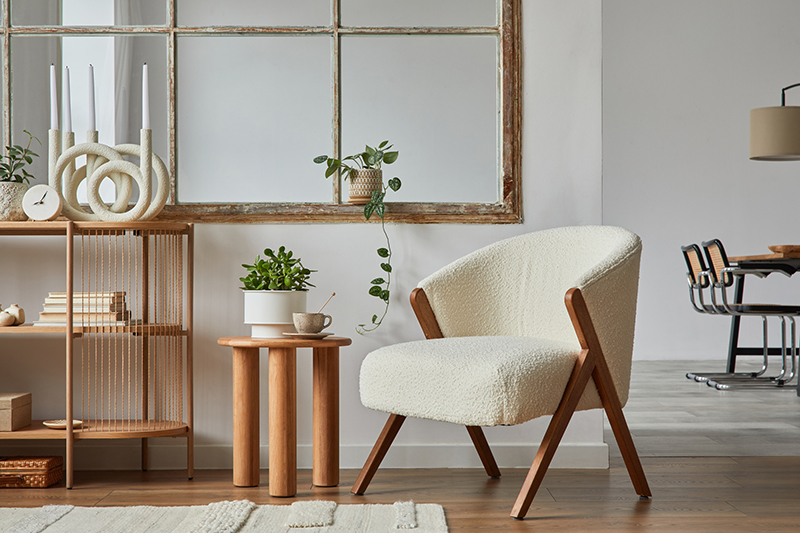 Stylish compositon of modern living room interior with frotte armchair, wooden commode, side table and elegant home accessories. Home staging. Template. Copy space."nDining room in the background."n